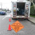 City sign notifying of flushing in progress with truck in background.